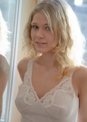 Сексуальная молоденькая блондинка Валя снимает белое нижнее белье перед окном