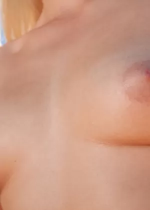 Обнаженная модель Анита Э принимает уверенные позы во время фотосессии на берегу моря на закате