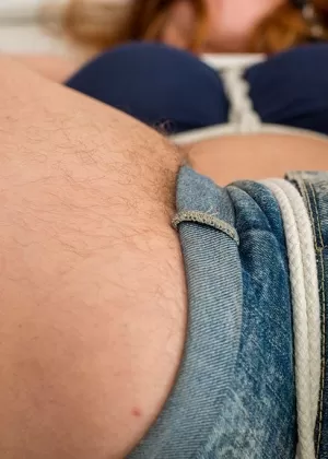 Сексуальная рыжая с волосатыми подмышками связана веревками и с кляпом во рту на кровати