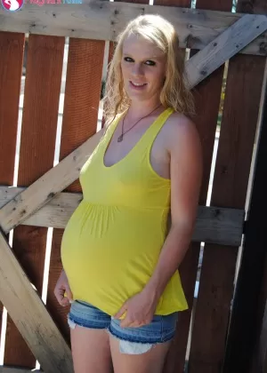 Беременная девушка Мартина стоит голая, насколько это возможно, сняв всю свою одежду