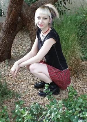 Татуированная блондинка Симона позирует обнаженной на открытом воздухе в плиссированной юбке