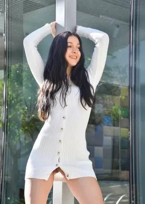 Темноволосая девушка раздевается во время переодевания на общественном тротуаре