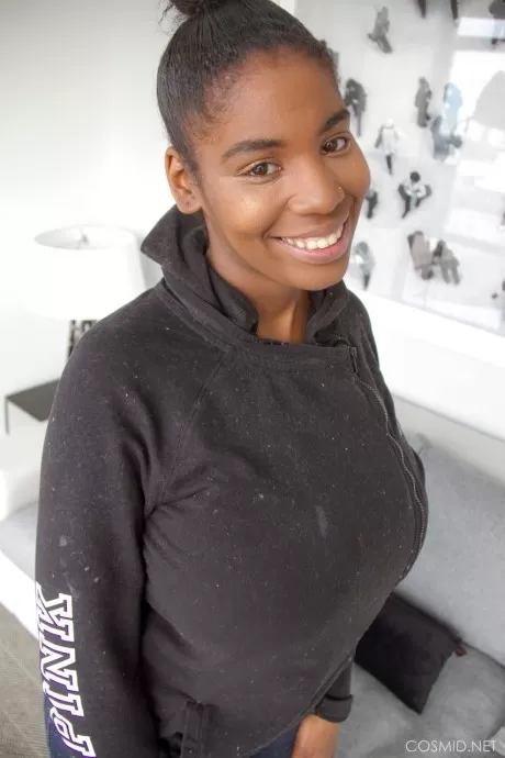 Улыбающаяся негритянка красотка снимает рубашку, чтобы выставить напоказ свои массивные больш