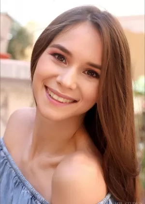 Красивая девушка поджимает губы после того, как обнажила свои маленькие сиськи в саду