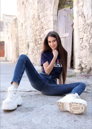 Симпатичная девушка с длинными волосами стягивает джинсы, чтобы показать свою киску и попку