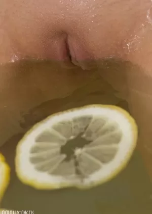 Симпатичная блондинка погружает свою лысую пизду в ванну, наполненную ломтиками лимона