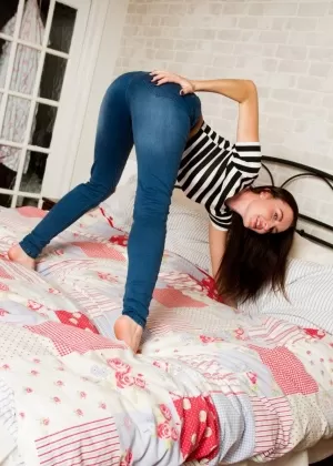 Гламурная модель София Смит обнажает свои маленькие сиськи на кровати в синих джинсах